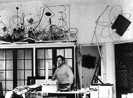 Alexander Calder in his shop with kinetic sculptures and materials